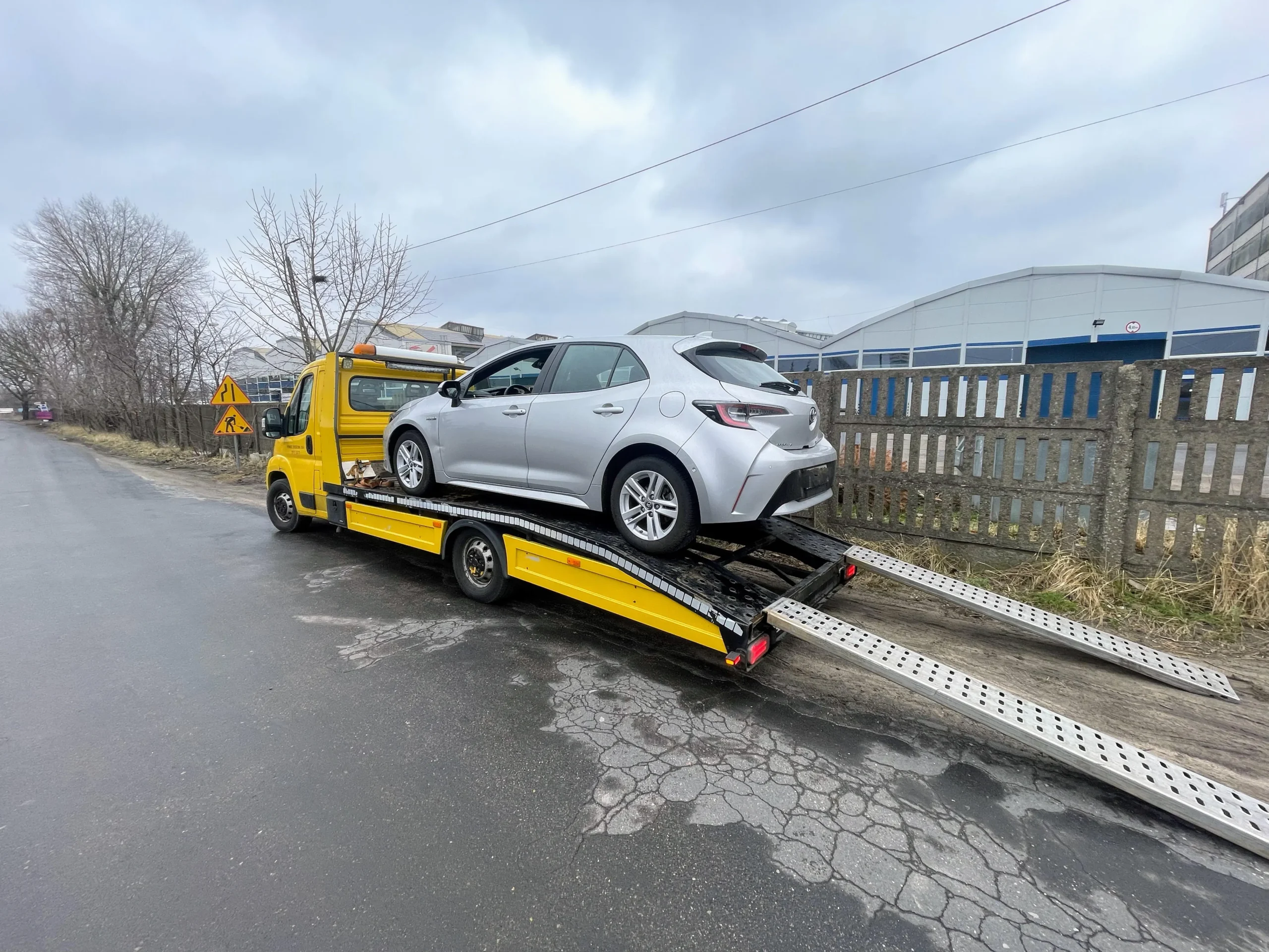 Srebrny Toyota Corolla hatchback bezpiecznie zabezpieczona pasami transportowymi na żółtej platformie autolawety KM Transport Szczecin.
